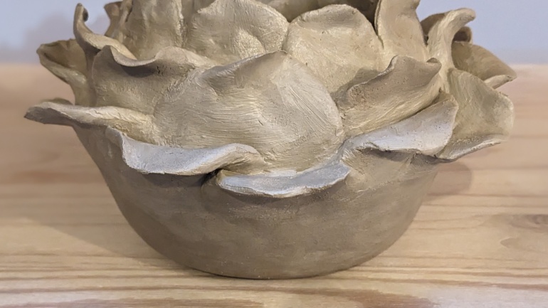a picture of a handmade clay pot with a leaf design made in a pottery course